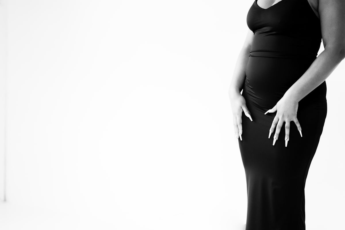 A pregnant woman in a black dress posing for a picture