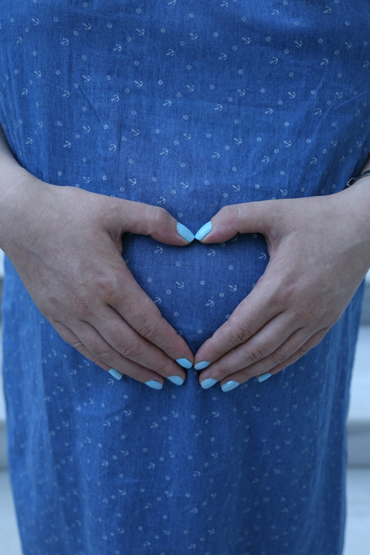 Woman forms heart shape over pregnant belly
