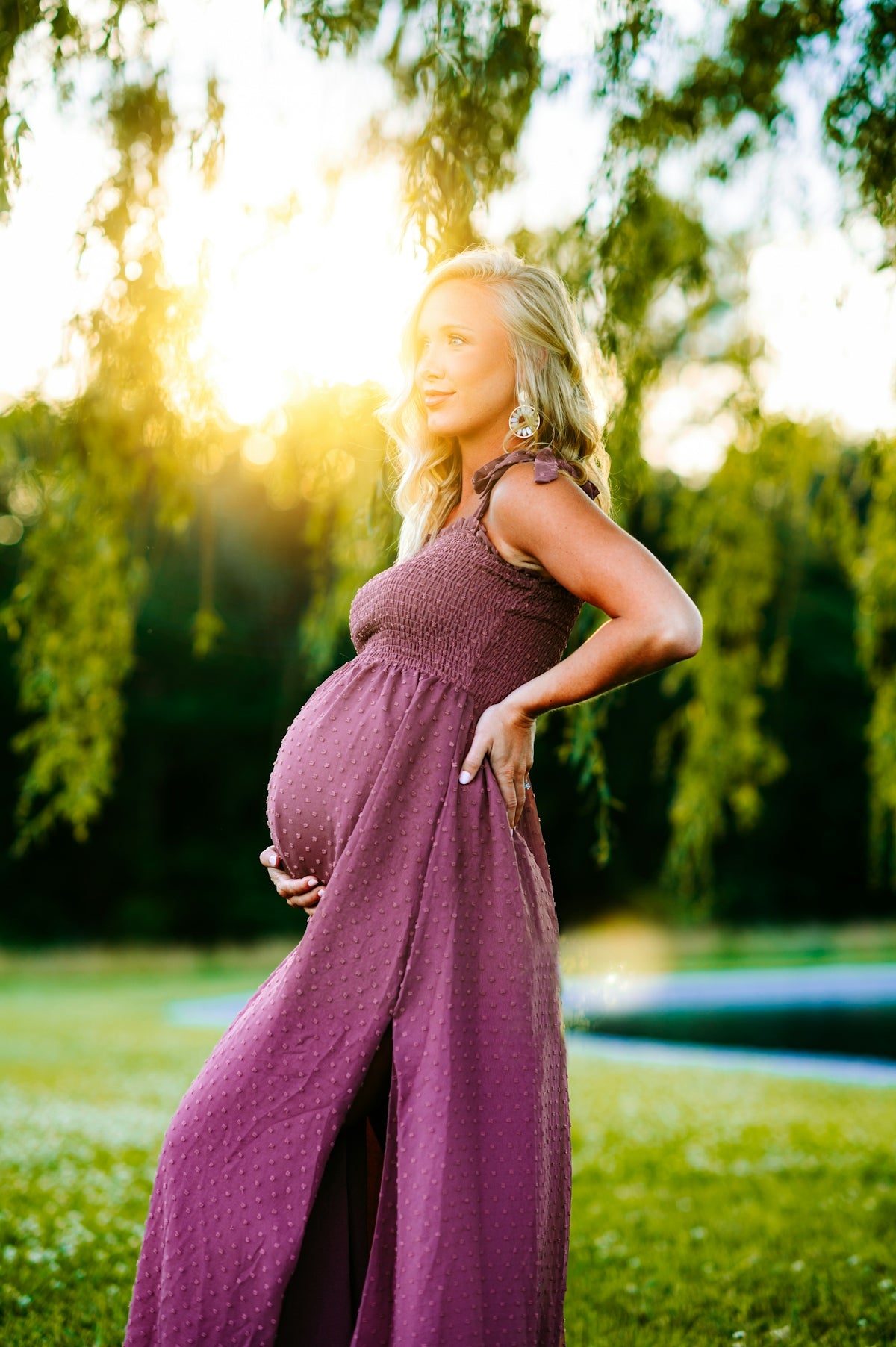 a pregnant woman in a purple dress poses for a picture