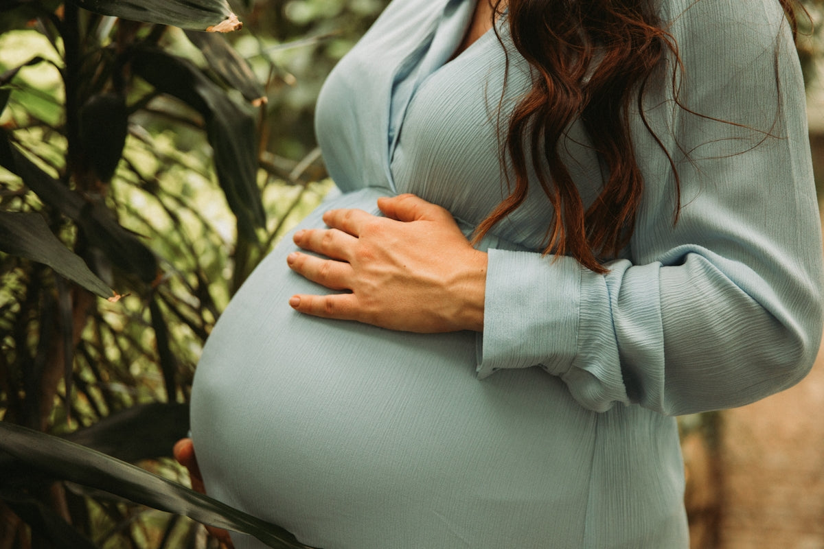 a pregnant woman standing in front of a tree
