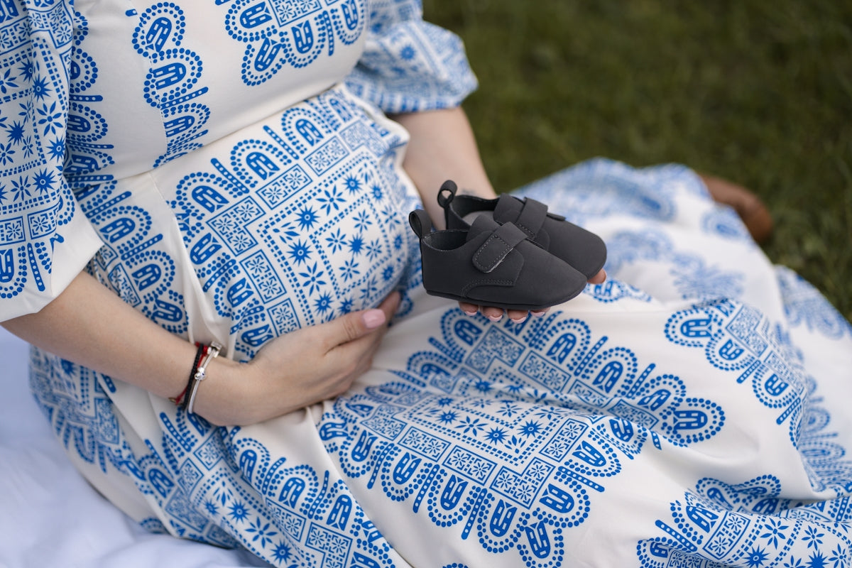 a pregnant woman in a blue and white dress holding a shoe