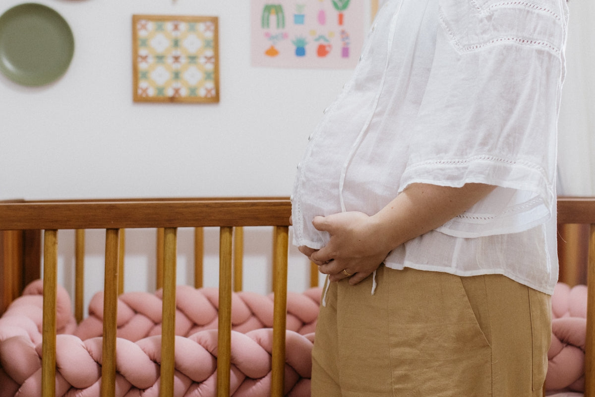 A woman standing in front of a baby crib