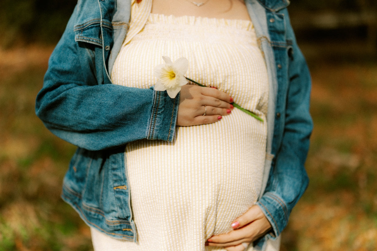 Pregnant woman holding a flower on her belly